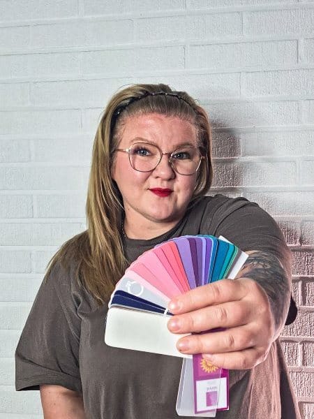 Väripaletti_ Pukeutumisneuvoja_450600 Nainen hymyilee kameraan, kädessä värianalyysi paletti